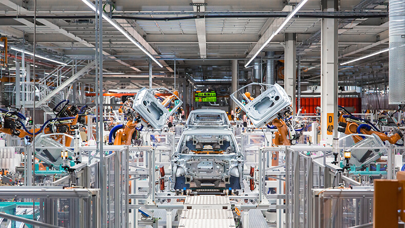 VW-Werk in Zwickau, Werkshalle mit Robotern, die Autoteile zusammensetzen.