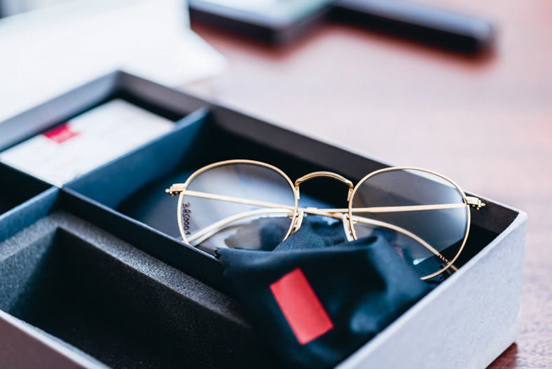 Nach Jahren des Wachstums erlitt die Augenoptikbranche 2020 einen Umsatzrückgang. Brille mit Goldrand liegt auf dunkem Tuch in einer Verpackungsschachtel.