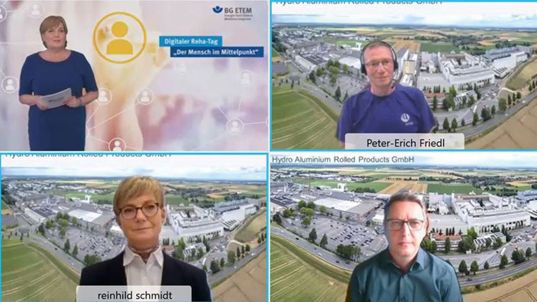 Eine Videokonferenz, die vier beteiligte Personen in vier Bildschirmen zeigt. Im Bild links oben steht am linken Bildrand eine Frau mit Merkblättern neben der Einblendung eines Menschensymbols und dem Text daneben: „Digitaler Reha-Tag“, in Anführungszeichen darunter: „Der Mensch im Mittelpunkt“. Oben rechts in diesem Bild ist auch das BG-ETEM-Logo eingeblendet. Der Name des Videokonferenz-Teilnehmers oben rechts ist in dessen Bildschirm eingeblendet: „Peter-Erich Friedl“.