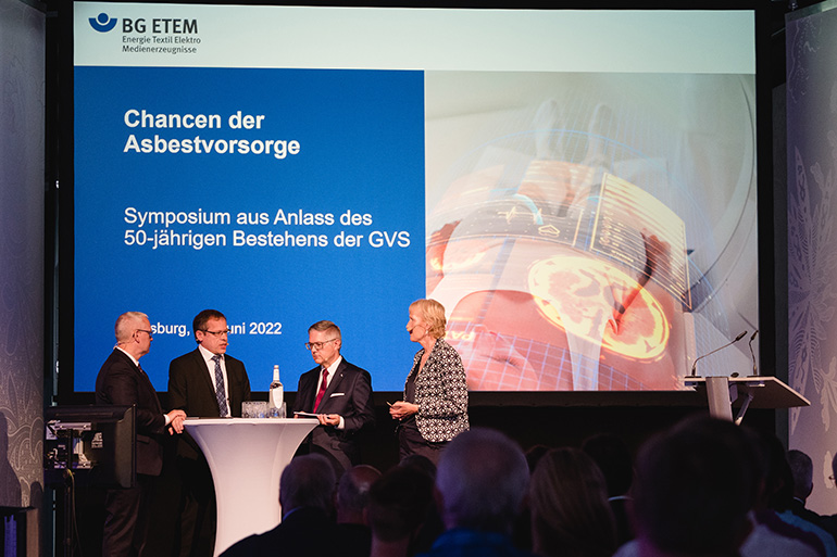 BG-ETEM-Führung steht auf einem Podium vor einer Leinwand zum Thema GVS.