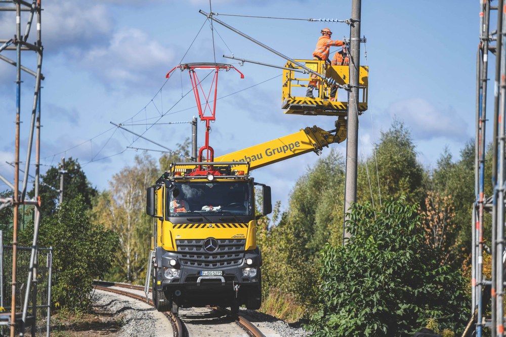 Ein Schienenfahrzeug wartet die elektrische Oberleitung an einer Bahnstrecke.