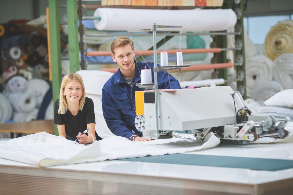 Ein Mädchen und ein junge besuchen eine Textilfabrik.