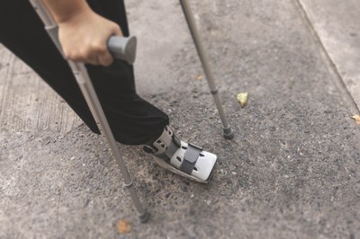 Ein Mensch läuft an Krücken und ist am Fuss verletzt.